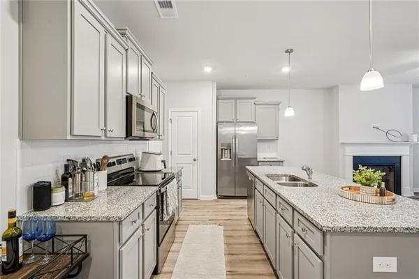 a kitchen with granite countertop stainless steel appliances a sink stove and refrigerator