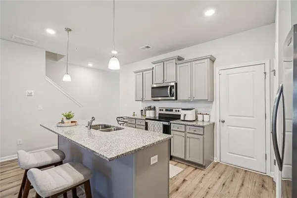 a kitchen with stainless steel appliances a sink a stove a refrigerator cabinets and living room view