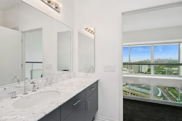 a bathroom with a granite countertop sink and a window