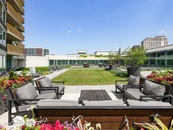 a view of a garden with lawn chairs and a table