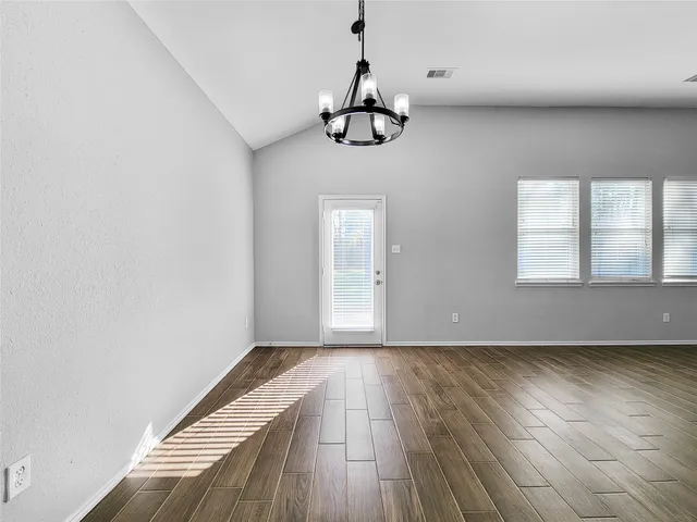 a view of an empty room with wooden floor and window