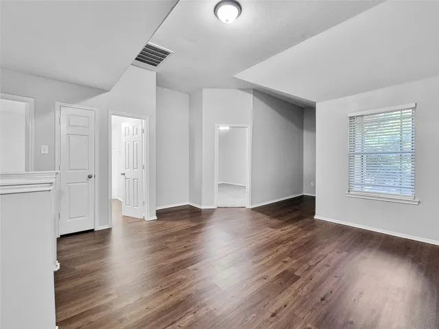 an empty room with wooden floor and windows