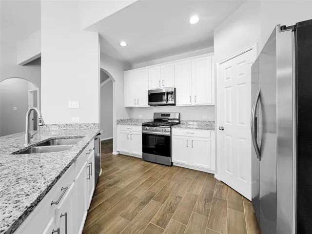 a kitchen with granite countertop a refrigerator stove and sink
