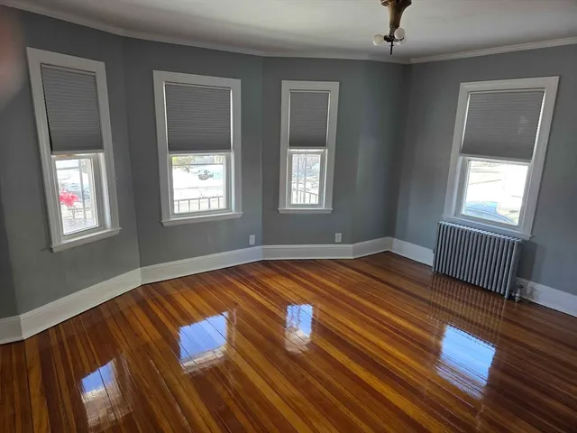 a view of empty room with window and wooden floor
