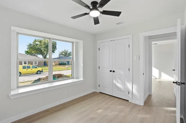 a view of an empty room with a window and a ceiling fan