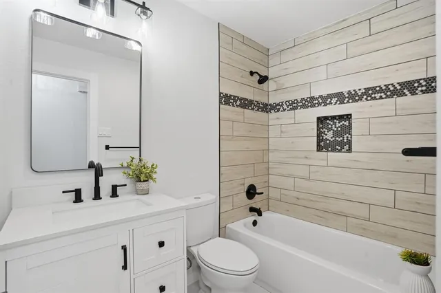 a bathroom with a bathtub shower sink vanity and toilet