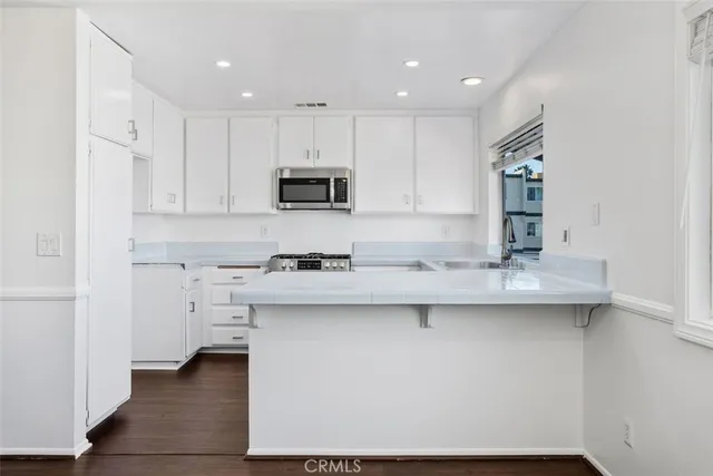 a kitchen with stainless steel appliances a sink stove and white cabinets