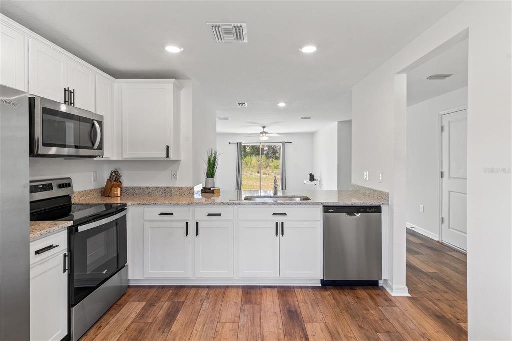 11380 Old Squaw Avenue Weeki Wachee, FL 34614 - Photo 7 of 23 a kitchen with stainless steel appliances granite countertop a stove a sink and a microwave