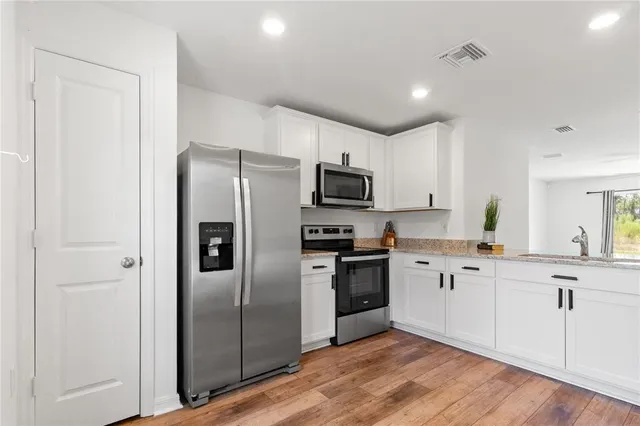 a kitchen with granite countertop a refrigerator stove top oven and sink