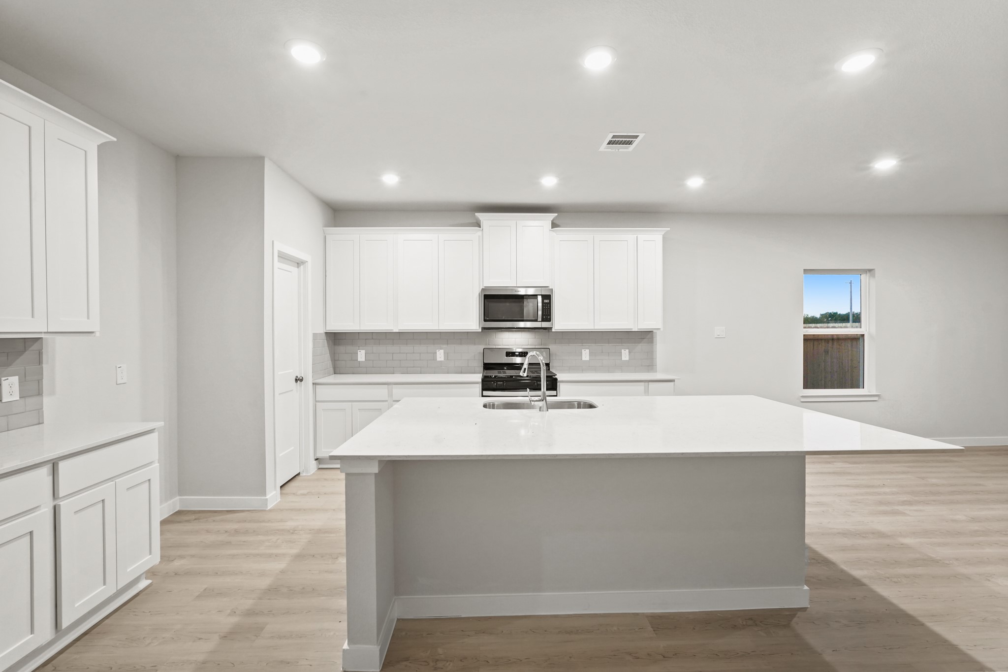 141 Byu Bnd Boulevard Angleton, TX 77515 - Photo 4 of 26 a large white kitchen with kitchen island white cabinets and stainless steel appliances