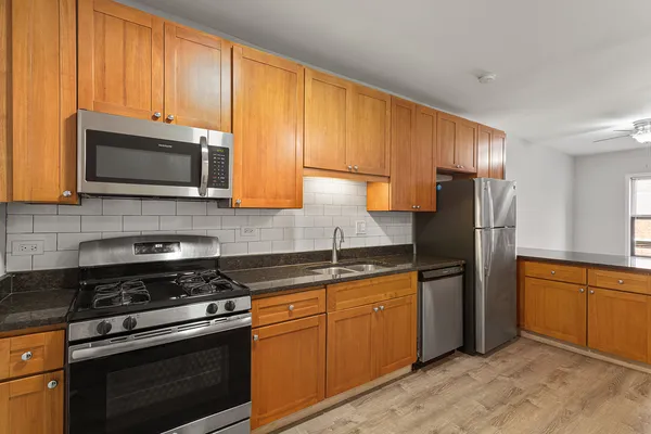 a kitchen with granite countertop wooden cabinets stainless steel appliances and a window