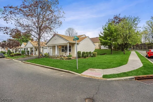 a view of a house with a small yard and a large tree