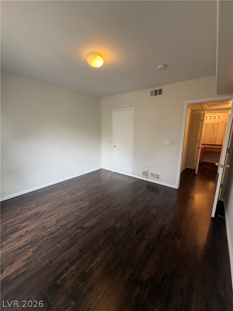 7255 West Sunset Road, Unit 2023 Las Vegas, NV 89113 - Photo 17 of 24 Rich dark wood flooring anchors this versatile space, offering seamless access to an adjacent bathroom.
