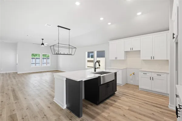 a kitchen with a sink a stove cabinets and wooden floor