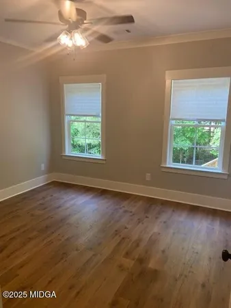 an empty room with wooden floor chandelier fan and windows