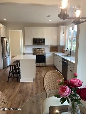 a kitchen with stainless steel appliances granite countertop a sink dishwasher a stove a refrigerator a microwave oven with cabinets and wooden floor