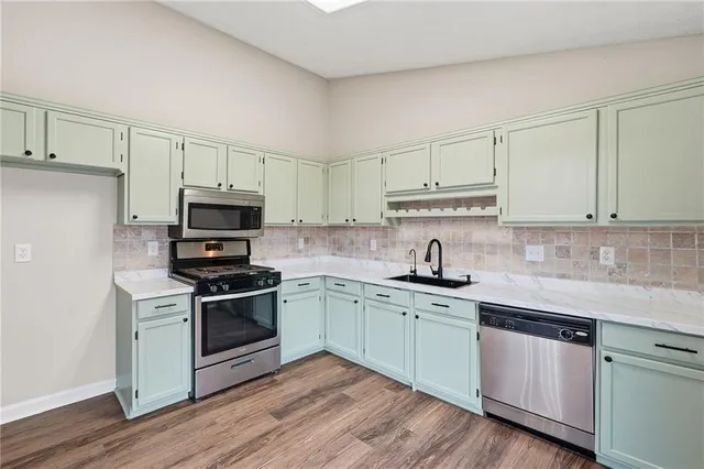 a kitchen with stainless steel appliances granite countertop a sink stove cabinets and wooden floor