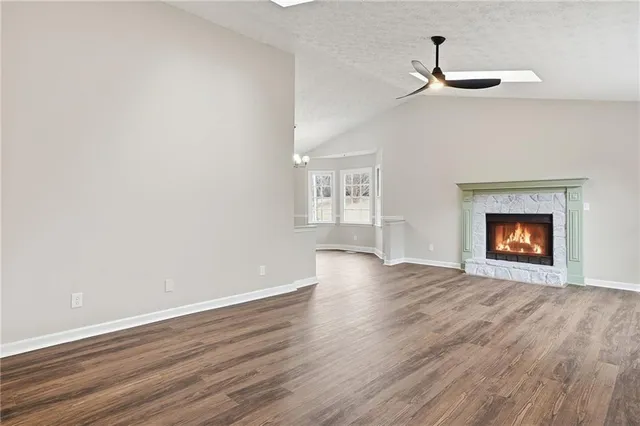 a view of an empty room with wooden floor fireplace and a window