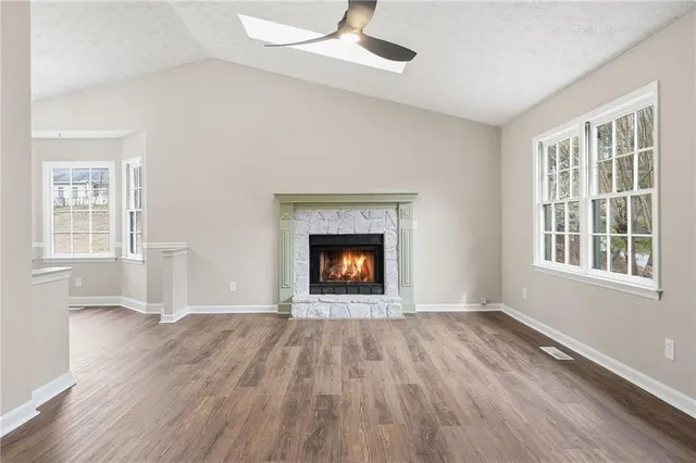 a view of an empty room with wooden floor fireplace and a window