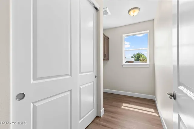 a view of a hallway with wooden floor and a bathroom