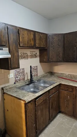 a kitchen with kitchen island granite countertop a sink a stove and cabinets