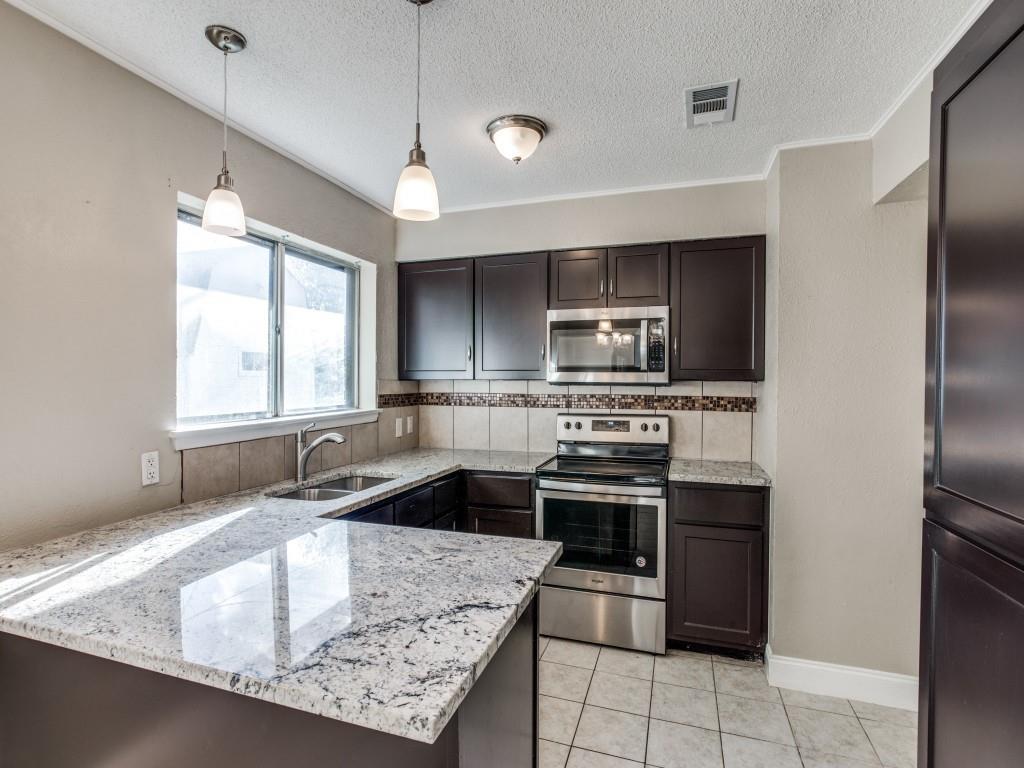 301 Springwillow Road Burleson, TX 76028 - Photo 6 of 12 Kitchen featuring stainless steel appliances, hanging light fixtures, light stone counters, a textured ceiling, and dark brown cabinetry
