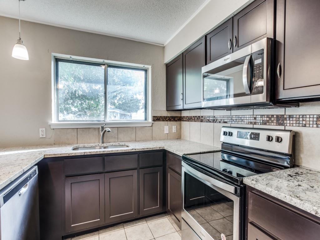 301 Springwillow Road Burleson, TX 76028 - Photo 7 of 12 Kitchen with appliances with stainless steel finishes, a textured ceiling, pendant lighting, light stone countertops, and light tile patterned flooring