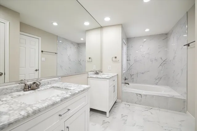 a bathroom with a granite countertop sink mirror and bathtub