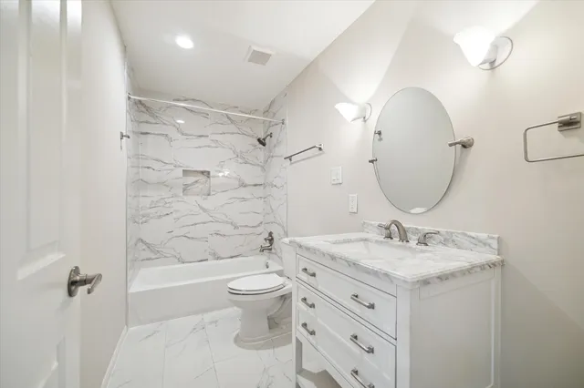 a bathroom with a granite countertop sink a toilet a mirror a bathtub and shower