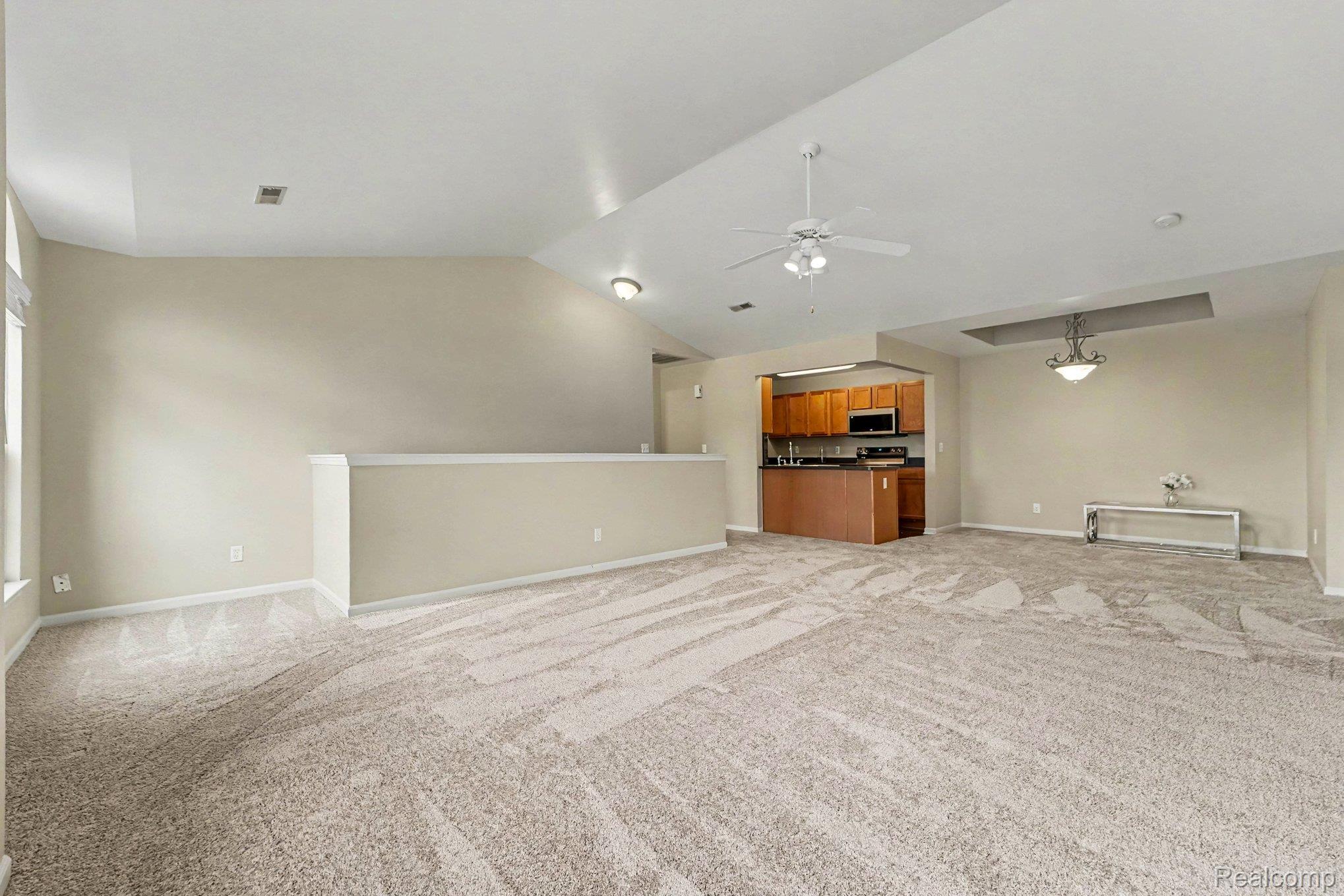 Unfurnished living room with light carpet and a ceiling fan