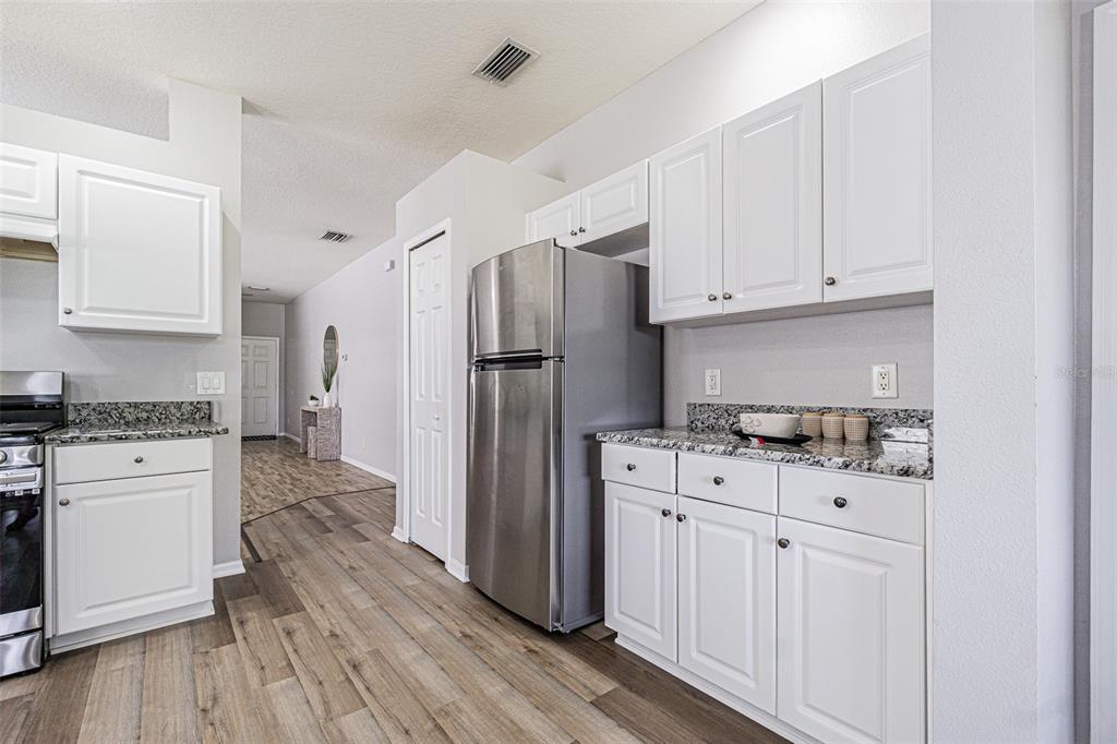 13016 Terrace Brook Place Temple Terrace, FL 33637 - Photo 7 of 27 a kitchen with white cabinets and stainless steel appliances