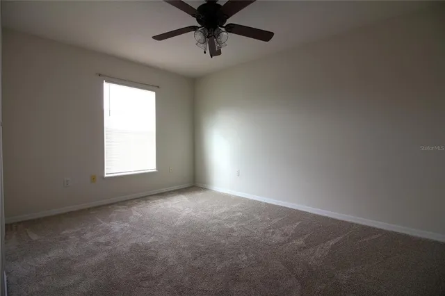 an empty room with a window and a fan