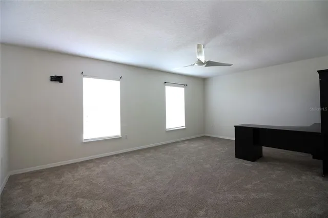 an empty room with windows and fan