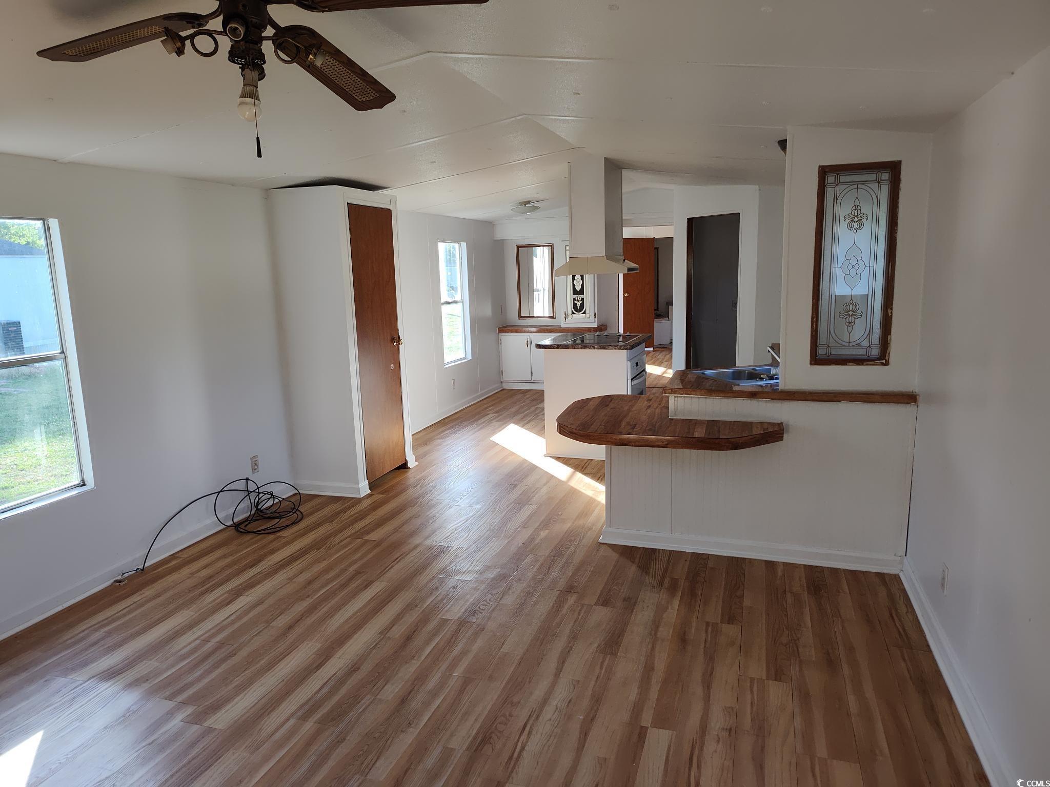 43 Newton Trail Andrews, SC 29510 - Photo 3 of 7 Kitchen featuring ceiling fan, a peninsula, vaulted ceiling, wood finished floors, and island range hood