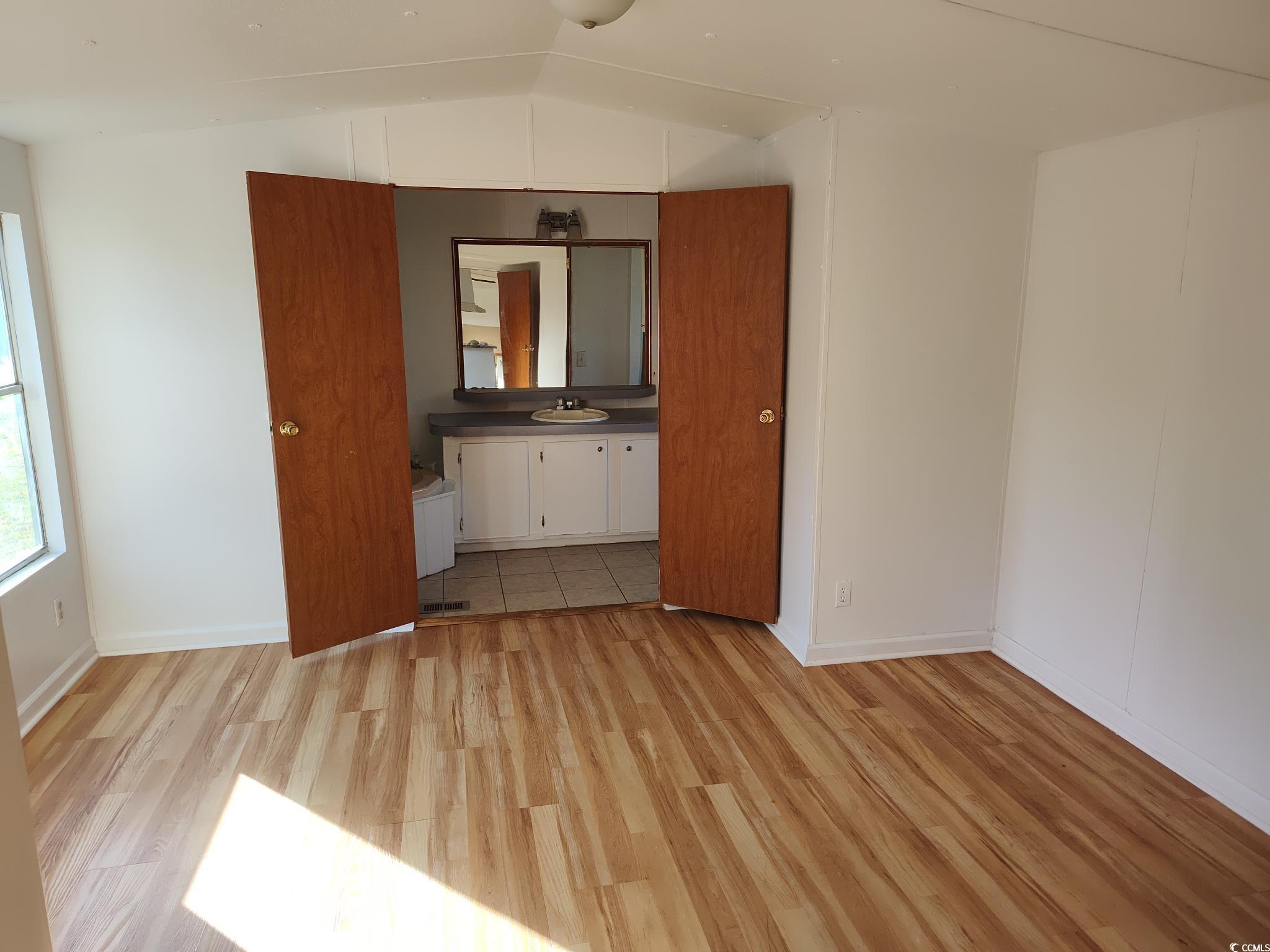 43 Newton Trail Andrews, SC 29510 - Photo 5 of 7 Unfurnished bedroom with baseboards, light wood finished floors, a sink, and vaulted ceiling