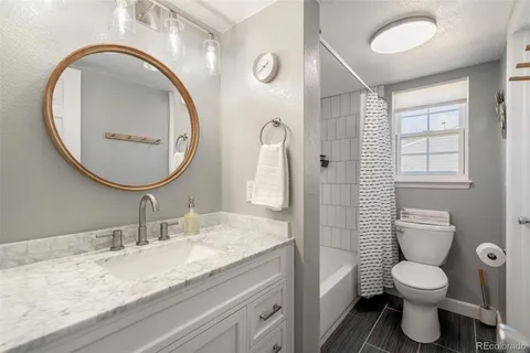 a bathroom with a granite countertop toilet a sink and a mirror