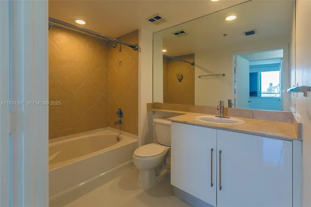 a bathroom with a granite countertop sink a toilet and shower