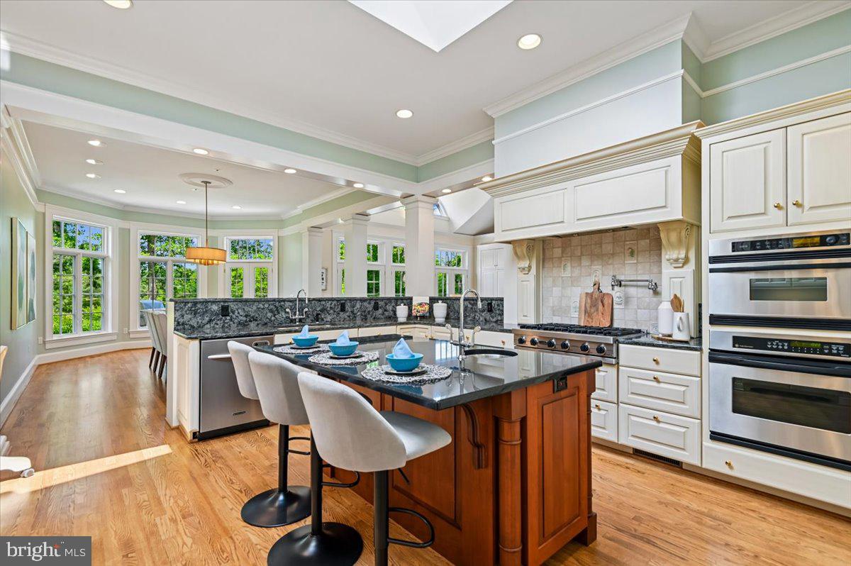 2700 Falling Timber Trail Edgewater, MD 21037 - Photo 22 of 89 a kitchen with stainless steel appliances granite countertop a stove top oven a refrigerator a dining table and chairs with wooden floor