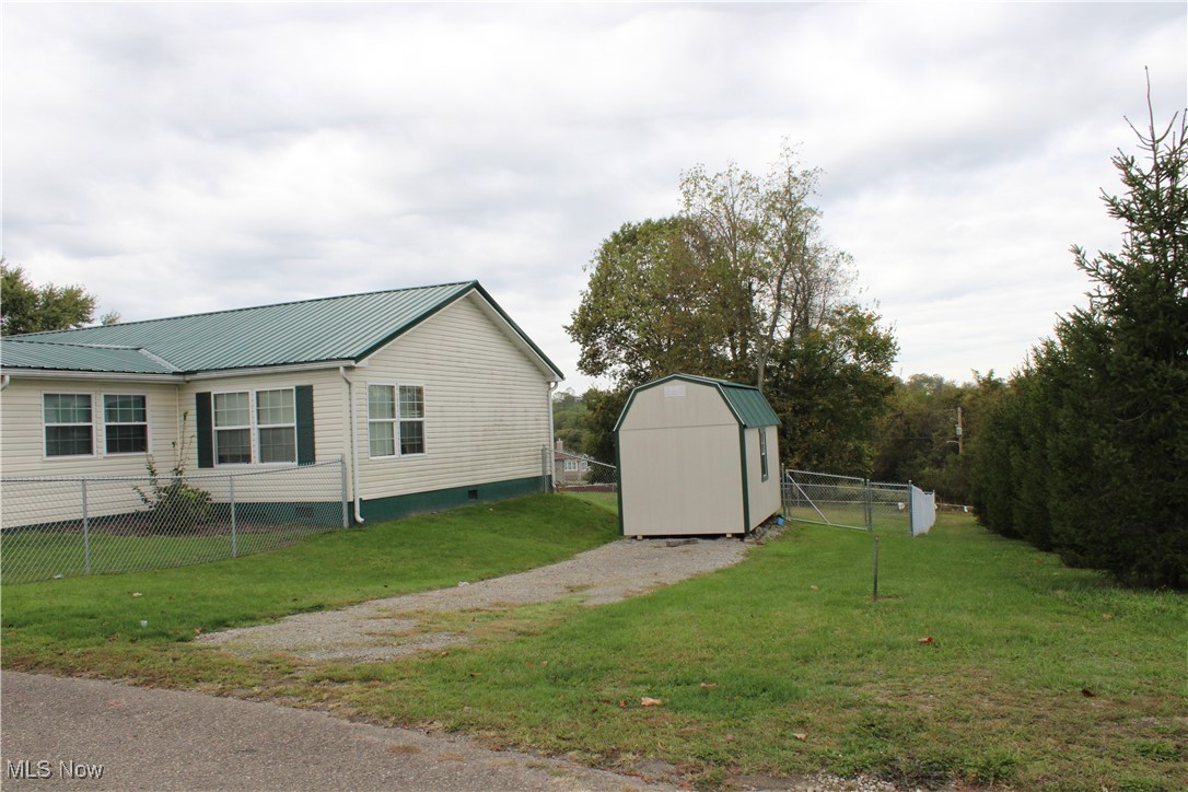 56 3rd Street Rayland, OH 43943 - Photo 4 of 46 View of home's exterior featuring crawl space, a metal roof, and a storage unit