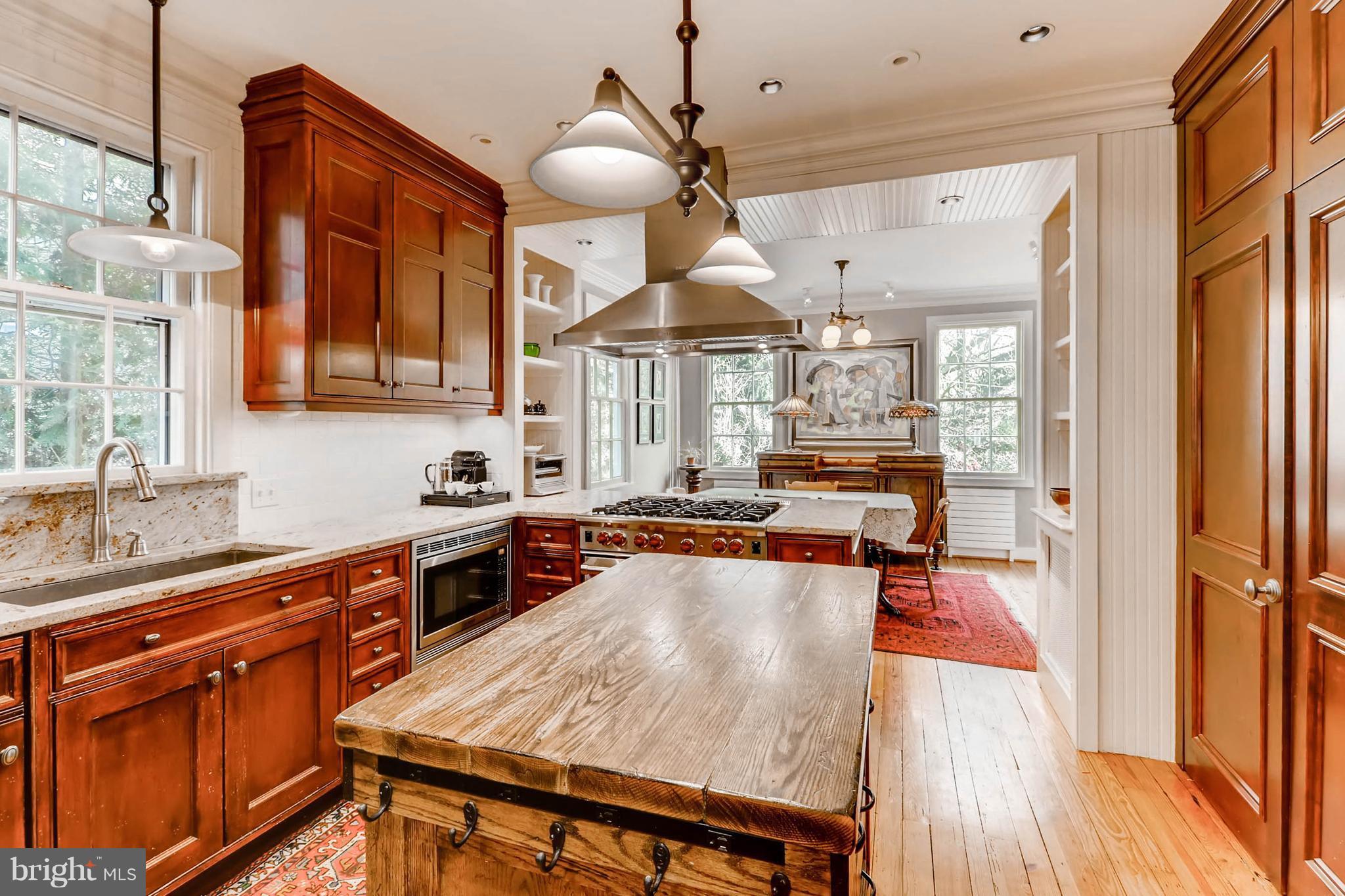 2326 Pickwick Road Baltimore, MD 21207 - Photo 11 of 30 a kitchen with stainless steel appliances a stove a sink dishwasher and a dining table with wooden floor