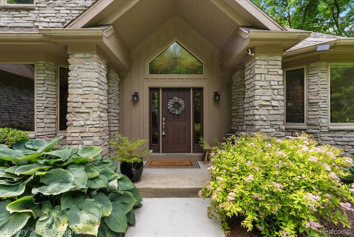 9867 Rainbow Ridge Drive Schoolcraft, MI 49087 - Photo 12 of 82 Stone-clad exterior featuring a prominent entryway with a dark wood front door, decorative transom window, and integrated outdoor lighting