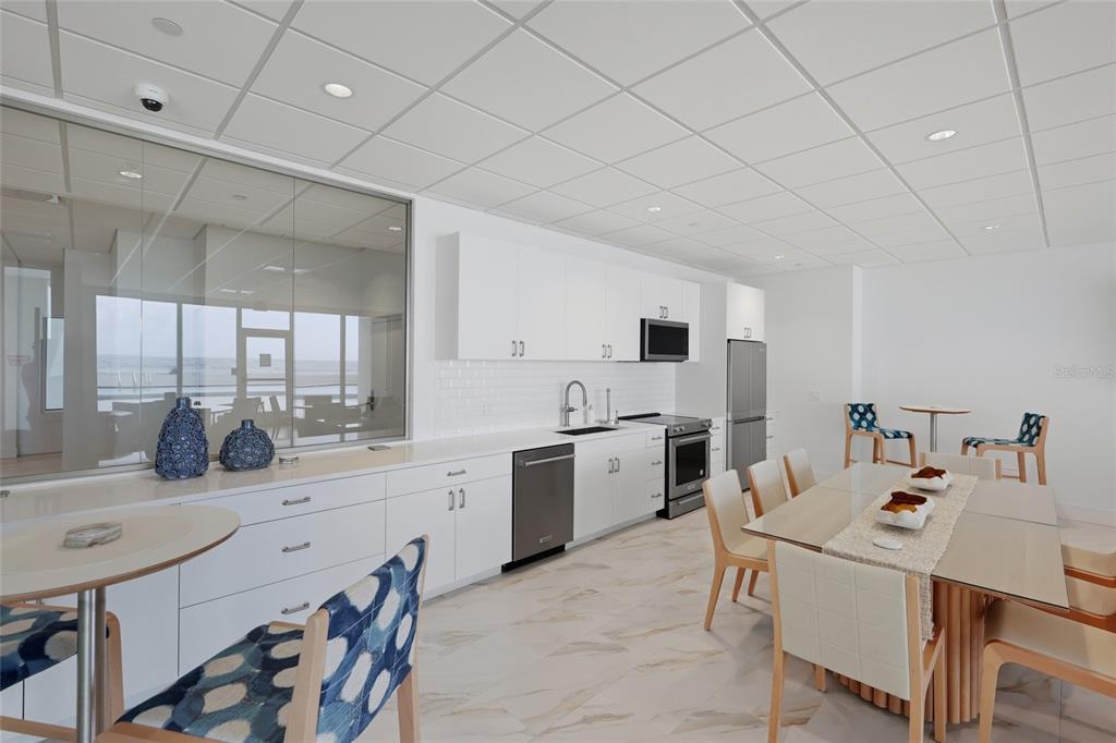 1750 Benjamin Franklin Drive, Unit 9B Sarasota, FL 34236 - Photo 31 of 47 a kitchen with a sink a stove and chairs