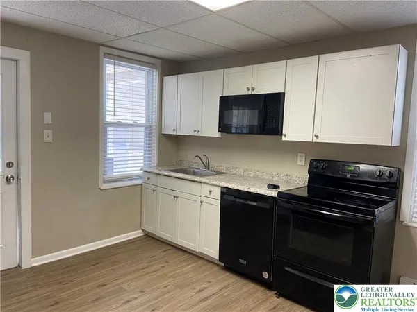 a kitchen with granite countertop a stove a sink and a microwave