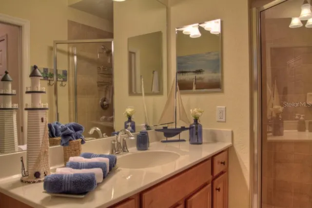 a bathroom with a granite countertop sink a mirror and shower