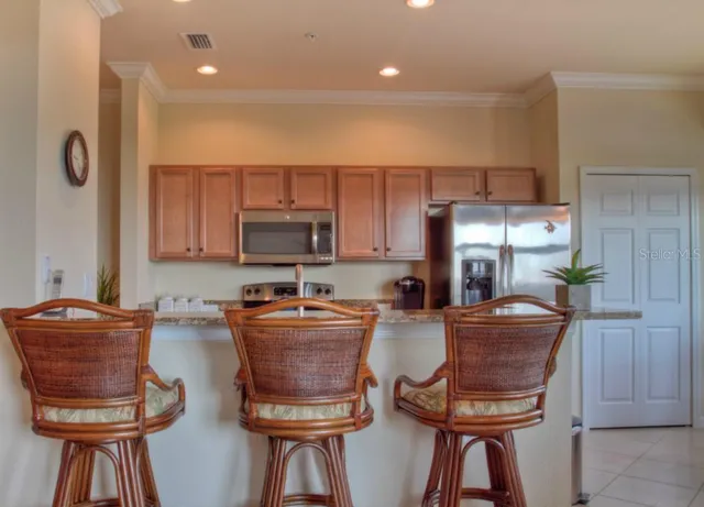 a kitchen with stainless steel appliances granite countertop a stove a refrigerator a sink a dining table and chairs with wooden floor