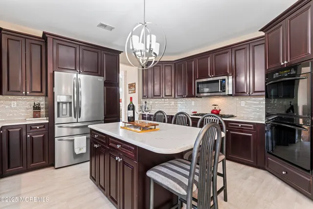 a kitchen with stainless steel appliances granite countertop a refrigerator a stove a sink dishwasher a dining table and chairs