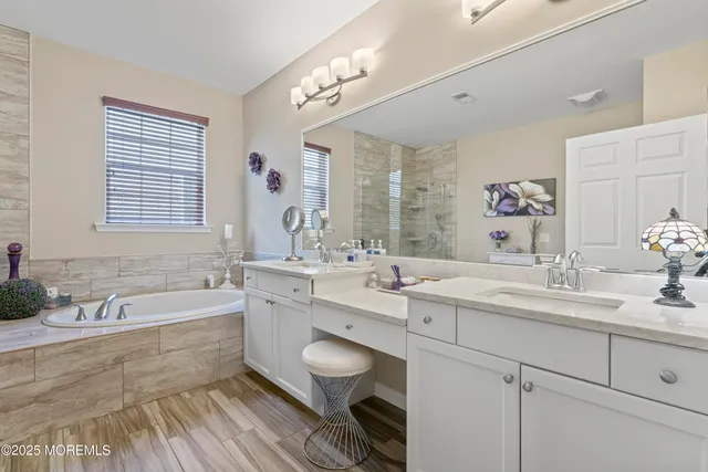 a spacious bathroom with a double vanity sink a large mirror a bathtub and window