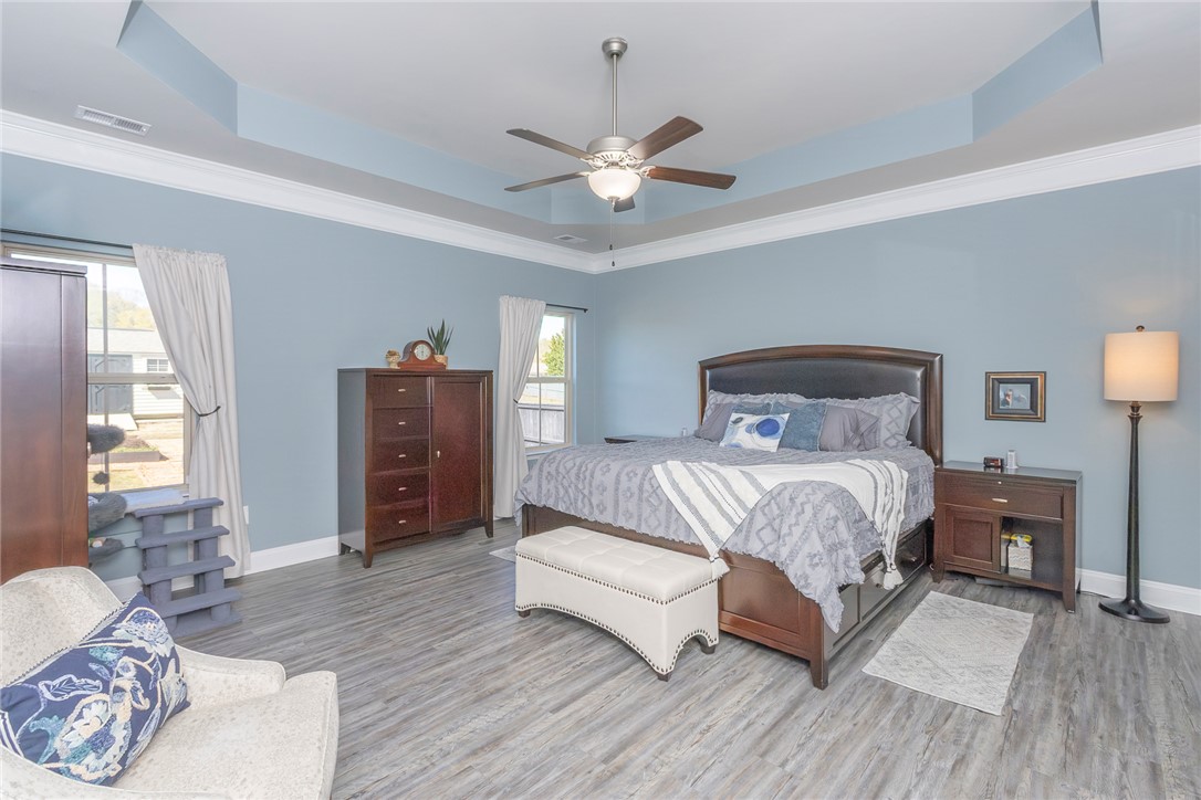203 Graceview West Anderson, SC 29625 - Photo 22 of 50 This spacious bedroom features a tray ceiling, crown molding, and stylish wood flooring, creating a comfortable retreat.