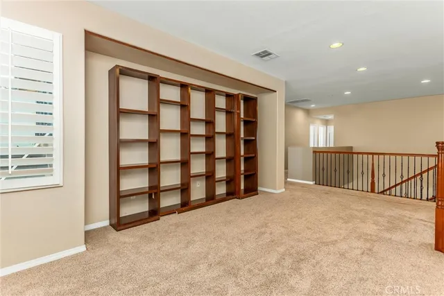 an empty room with a ceiling fan and carpet