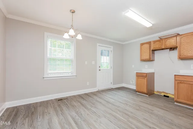 an empty room with wooden floor chandelier fan and windows